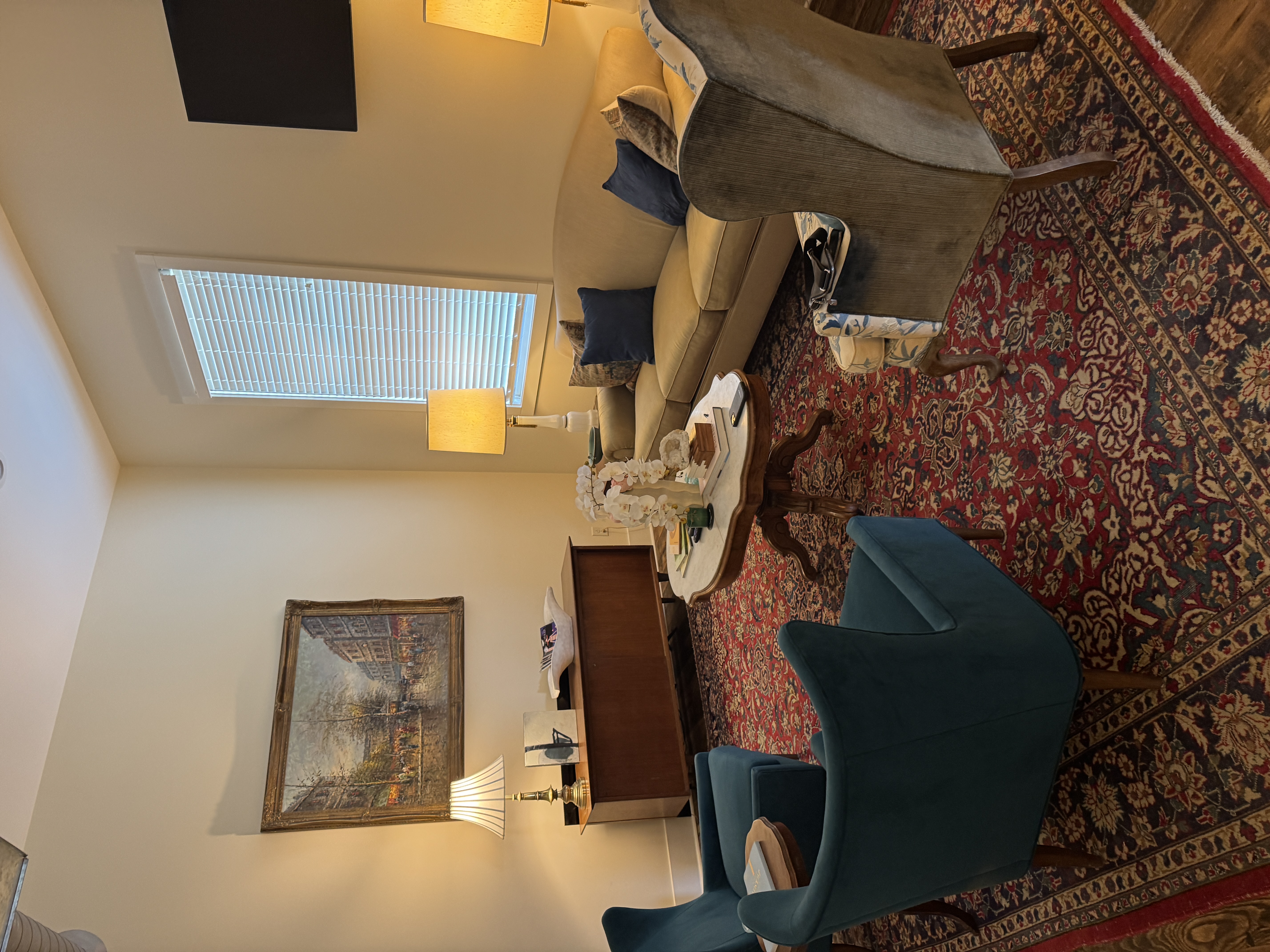 Warm counseling office interior with blue velvet chairs, sofa, ornate rug, lamps and a landscape painting at the Oxford office