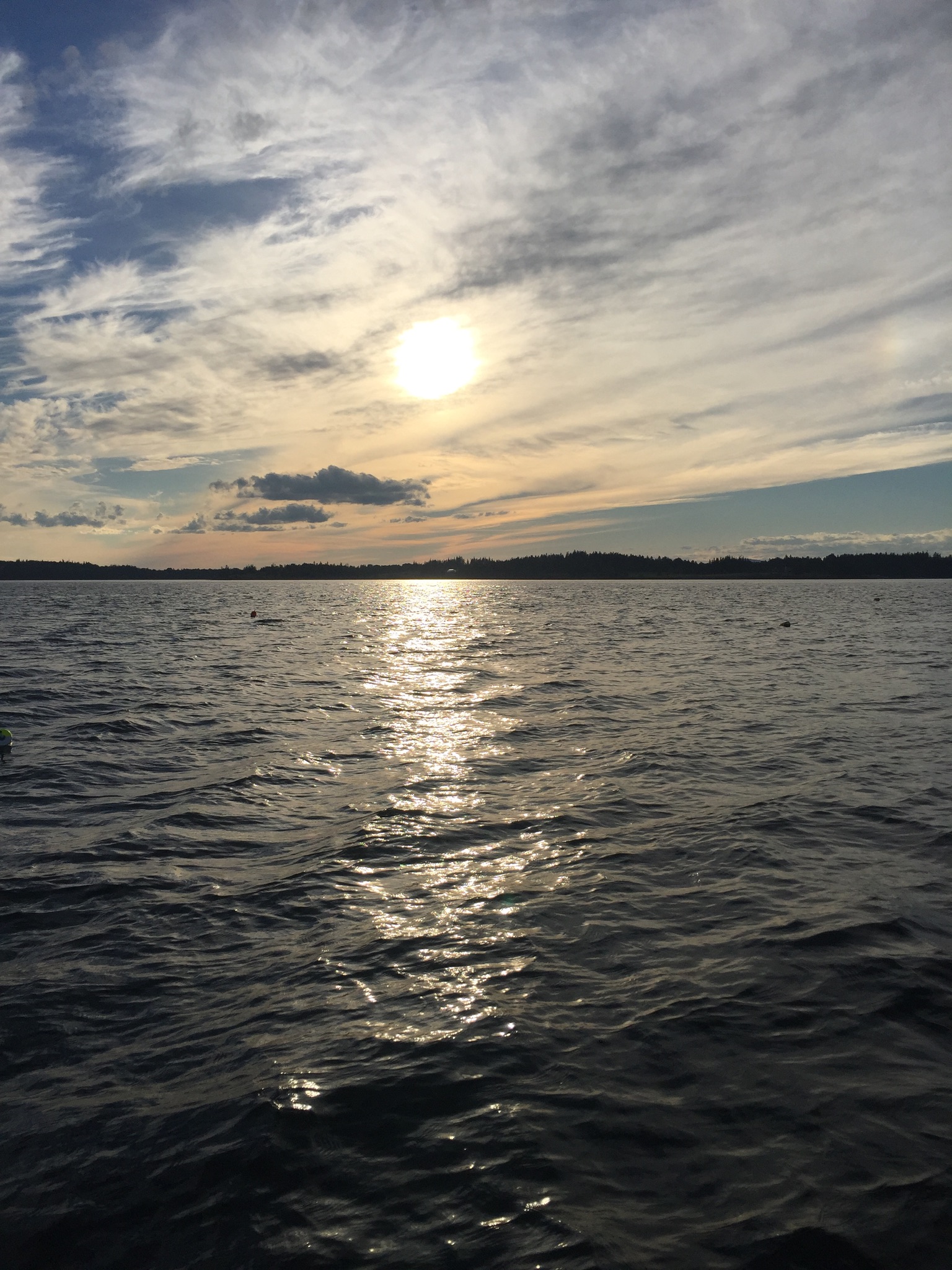 Sunset over a calm lake with dramatic clouds and a tree-lined horizon