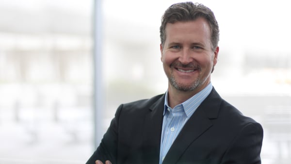 Michael Dolan, executive coach, smiling with arms crossed in a dark blazer