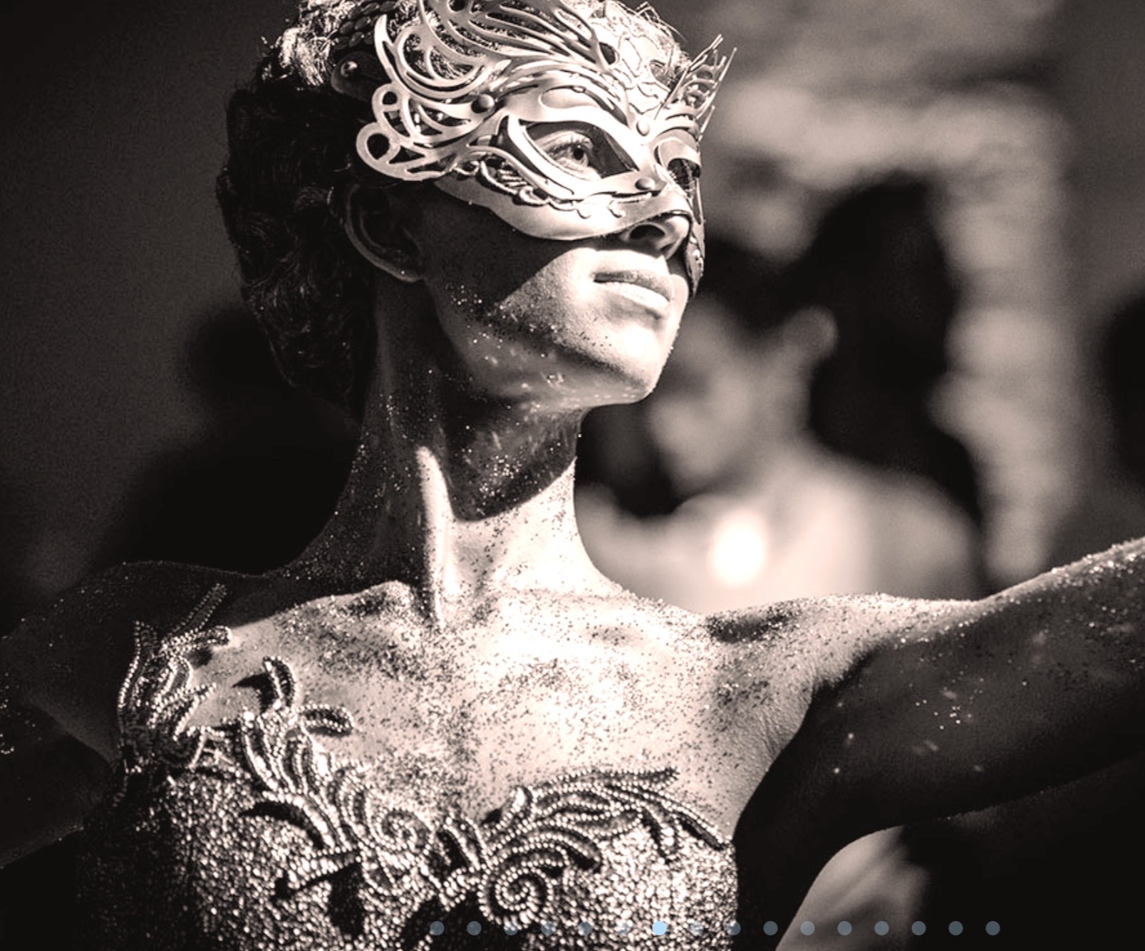 Performer in an ornate silver masquerade mask and jeweled costume