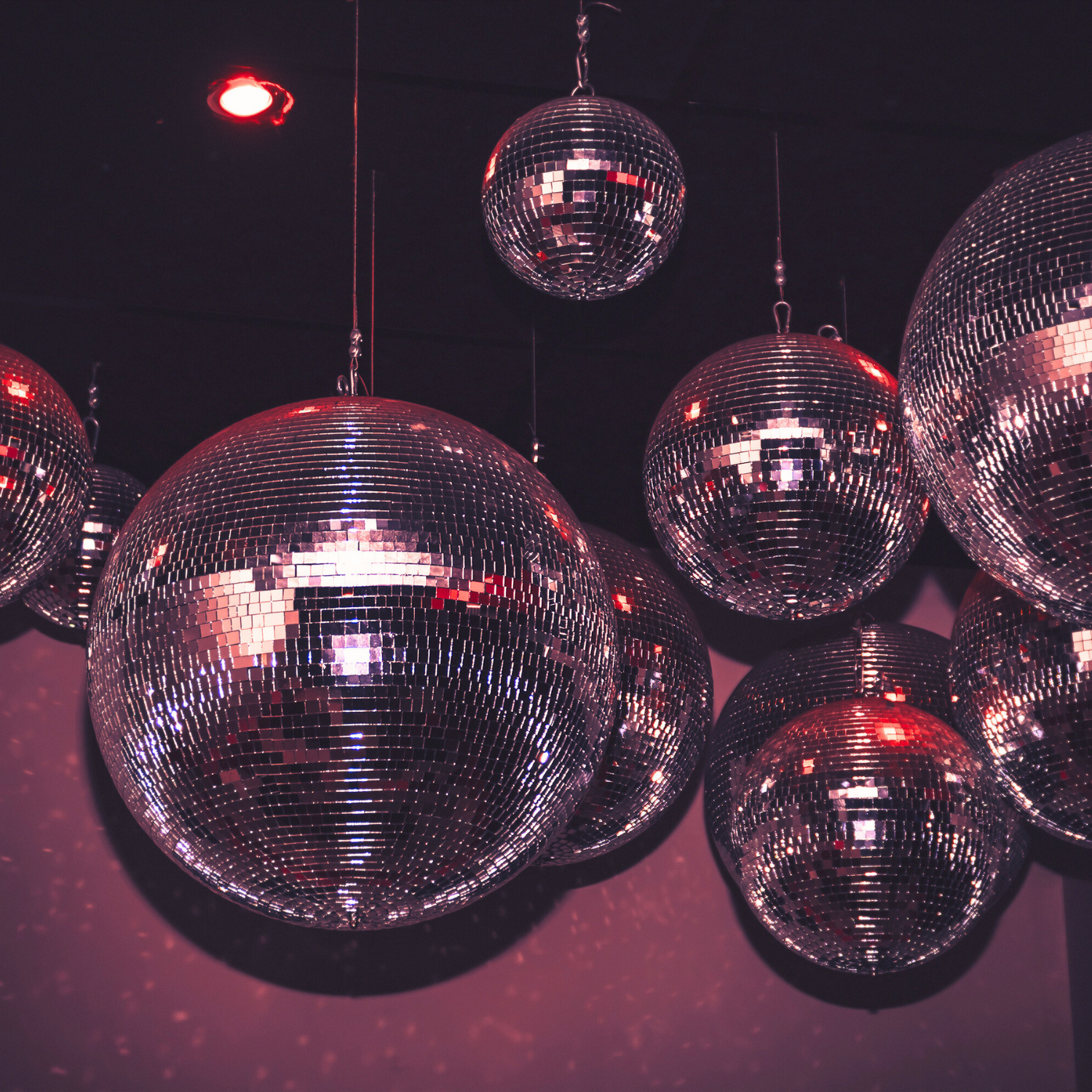 Cluster of mirror disco balls under red ambient lighting