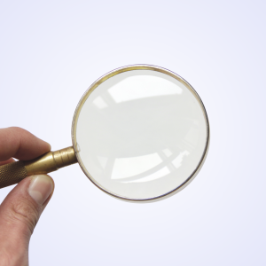 A hand holding a gold magnifying glass
