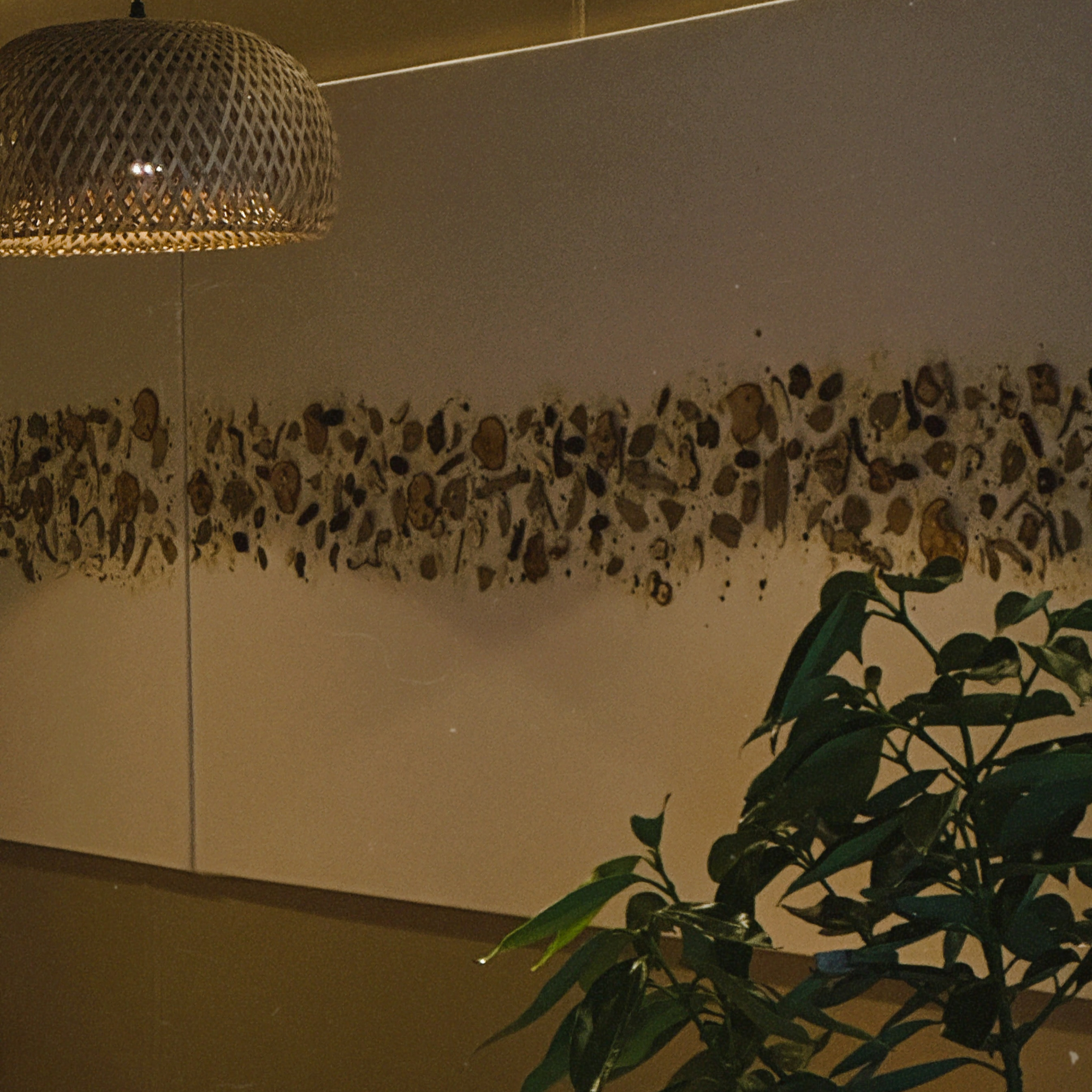 Twilight Lounge dining room: a speckled mural wall, a wicker pendant lamp and a tall indoor plant