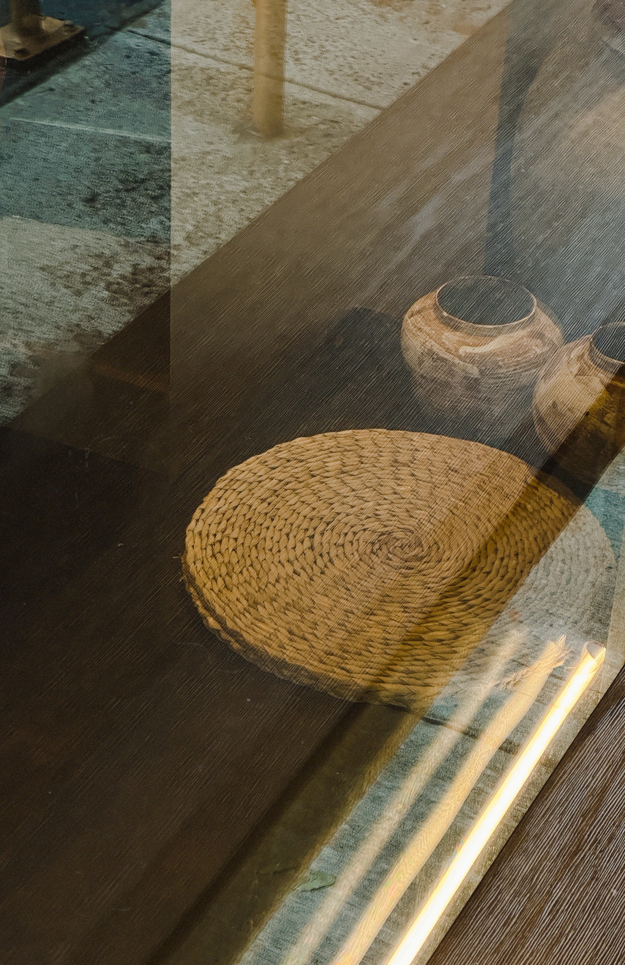 Close-up of a woven rattan place mat on a dark wooden table inside Twilight Lounge NYC