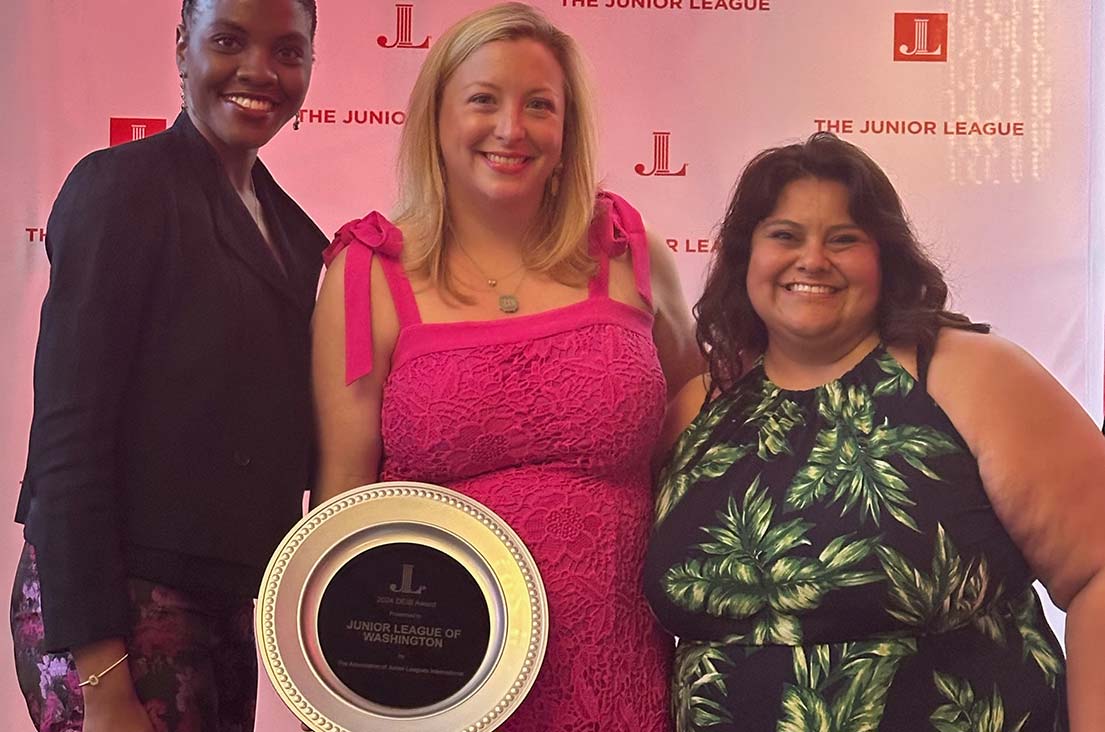 Three women holding a DEIAB award plaque at a Junior League of Washington event