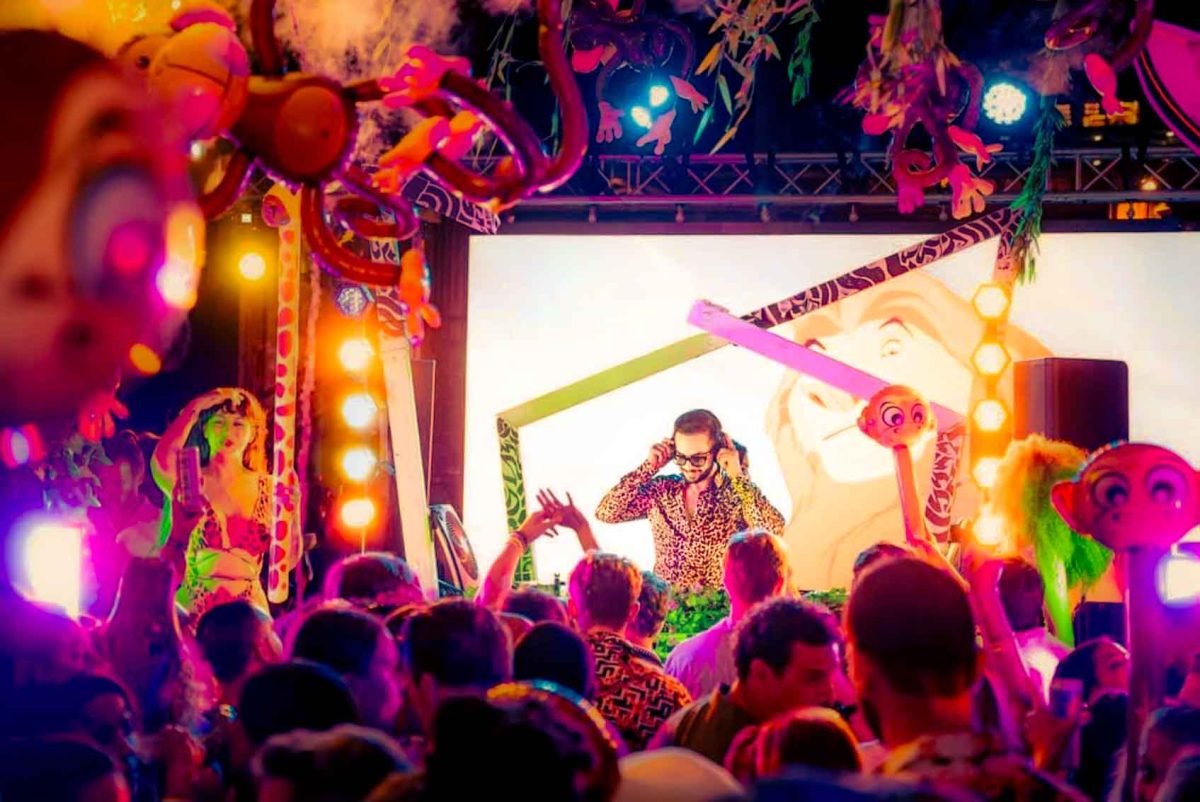 Colorful jungle and safari themed pop-up event stage with a DJ performing to a crowd