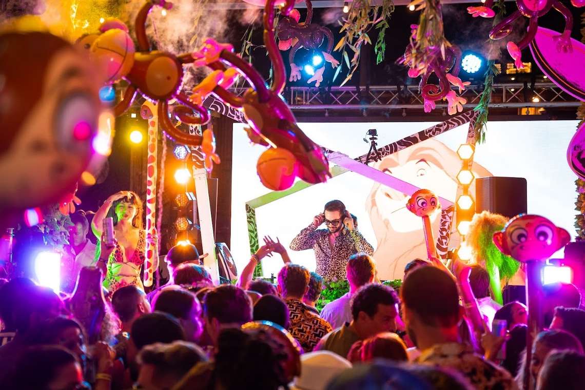 Colorful jungle-themed pop-up event stage with a DJ and crowd under elaborate hanging decorations