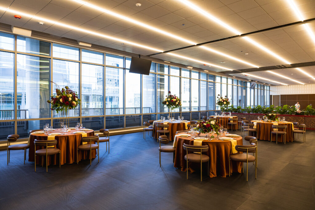 Elegant banquet hall with round tables, floral centerpieces and floor-to-ceiling windows