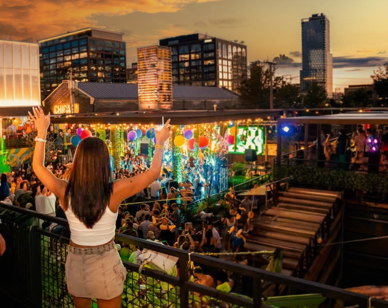Woman with arms raised over a packed rooftop party at sunset with the Chicago skyline