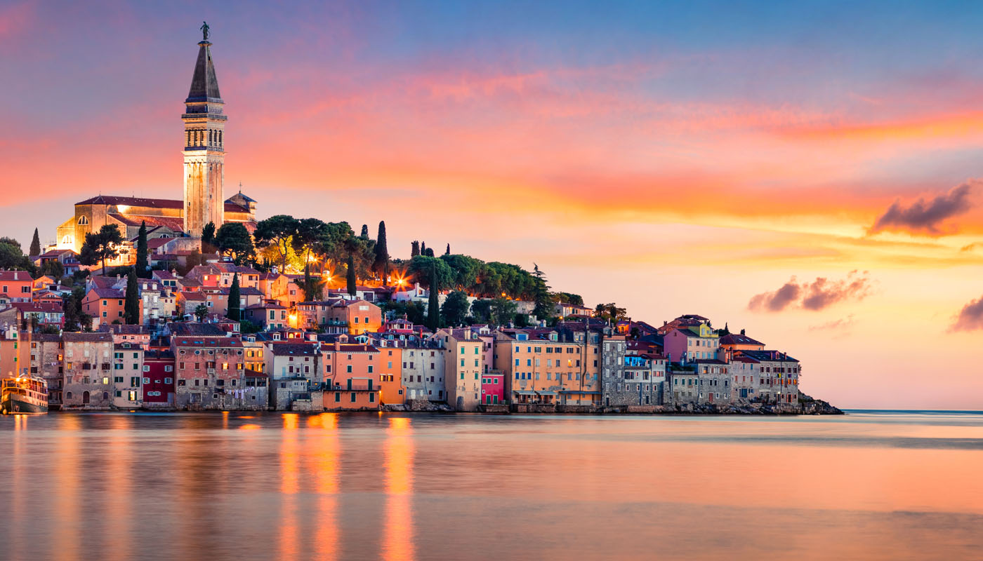 Sunset panorama of Rovinj with its bell tower and waterfront reflected in a calm sea