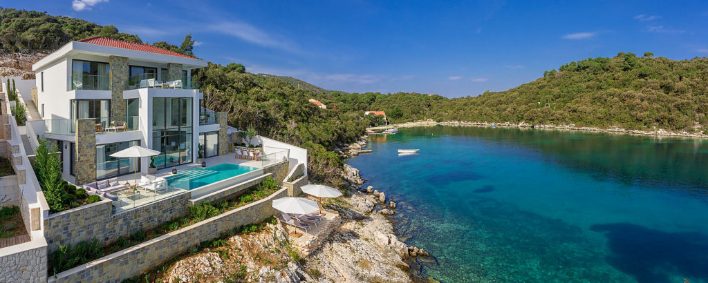 Aerial view of a modern luxury waterfront villa with pool on the rocky Croatian coastline