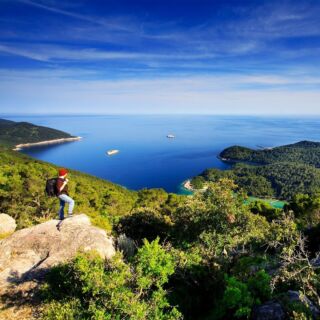 Instagram post: hiker on a rocky hilltop overlooking a Croatian island coastline