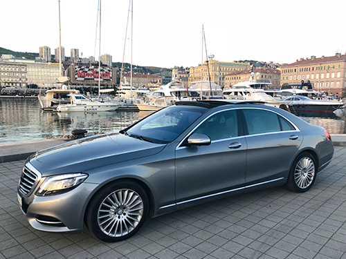 Grey Mercedes-Benz sedan parked at a marina with yachts