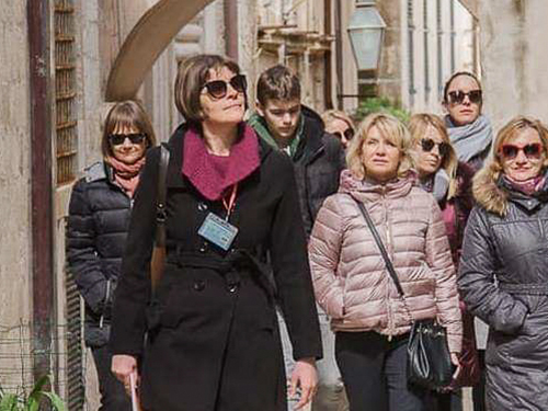 Female tour guide leading a group through a narrow historic stone alley