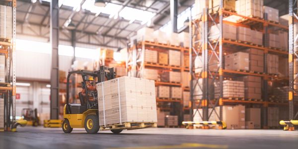 Forklift carrying pallets of boxes inside a large warehouse