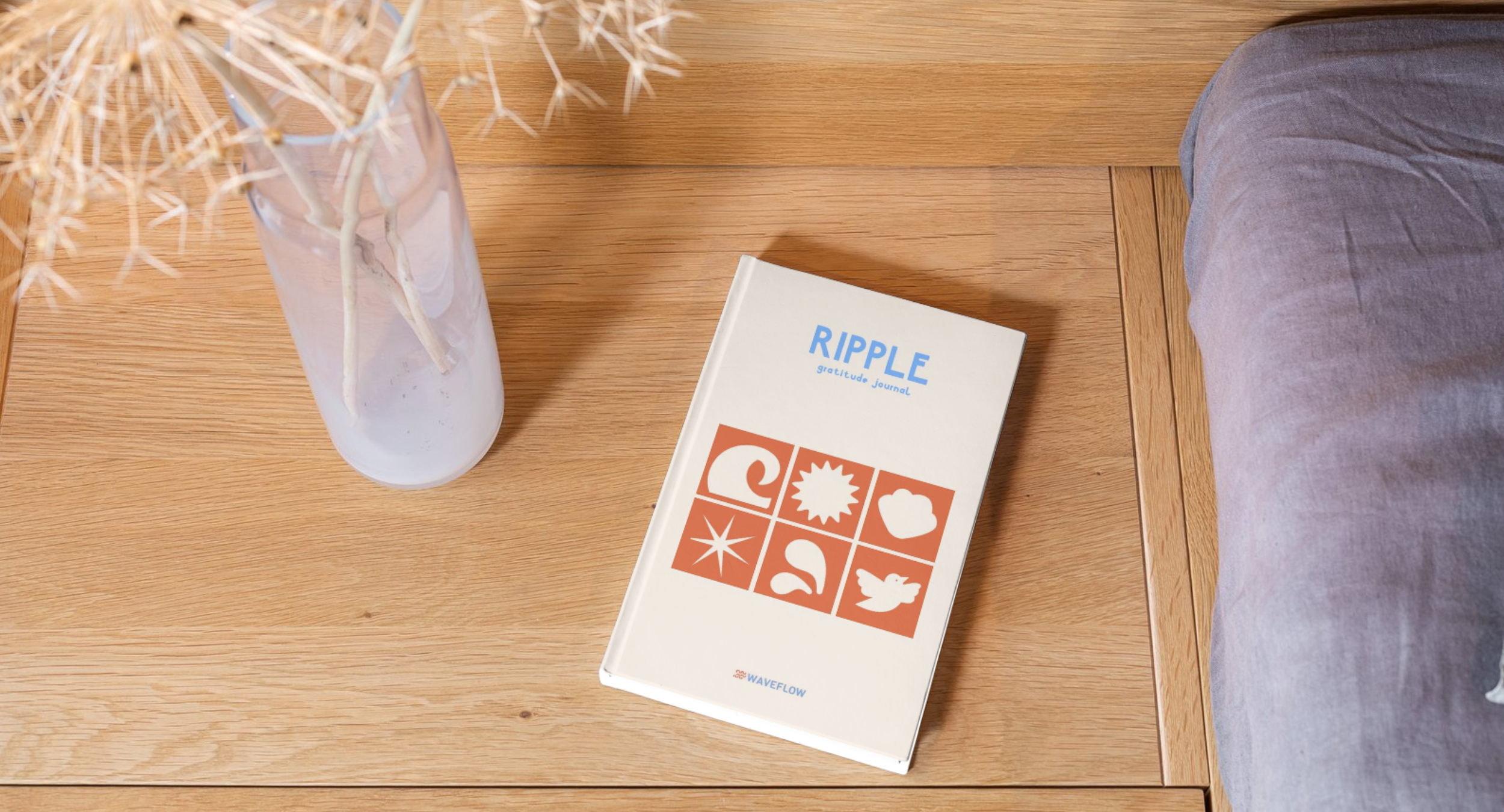 Ripple gratitude journal on an oak table beside dried flowers and bedding