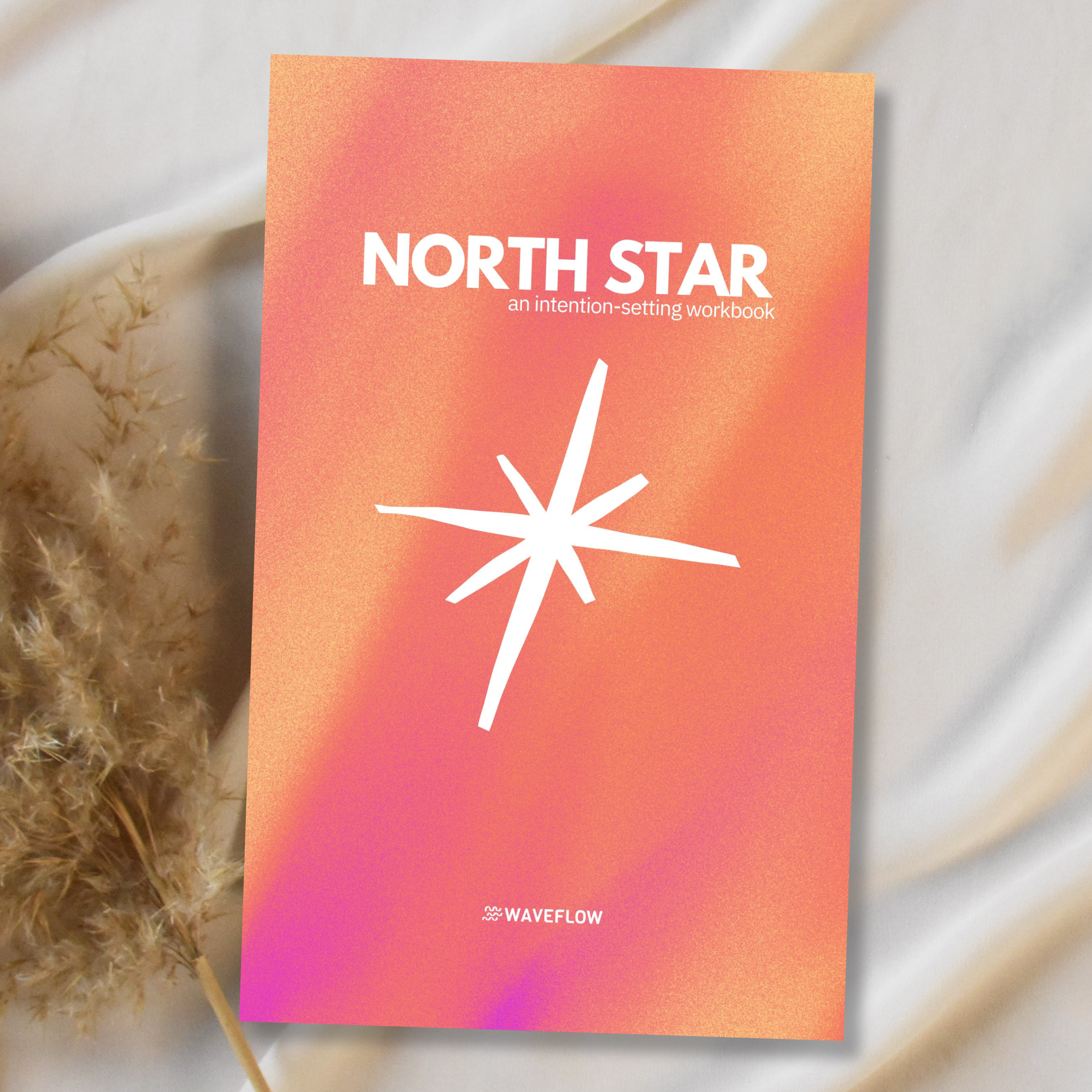 North Star Intention Setting Workbook lying on white fabric with dried pampas grass