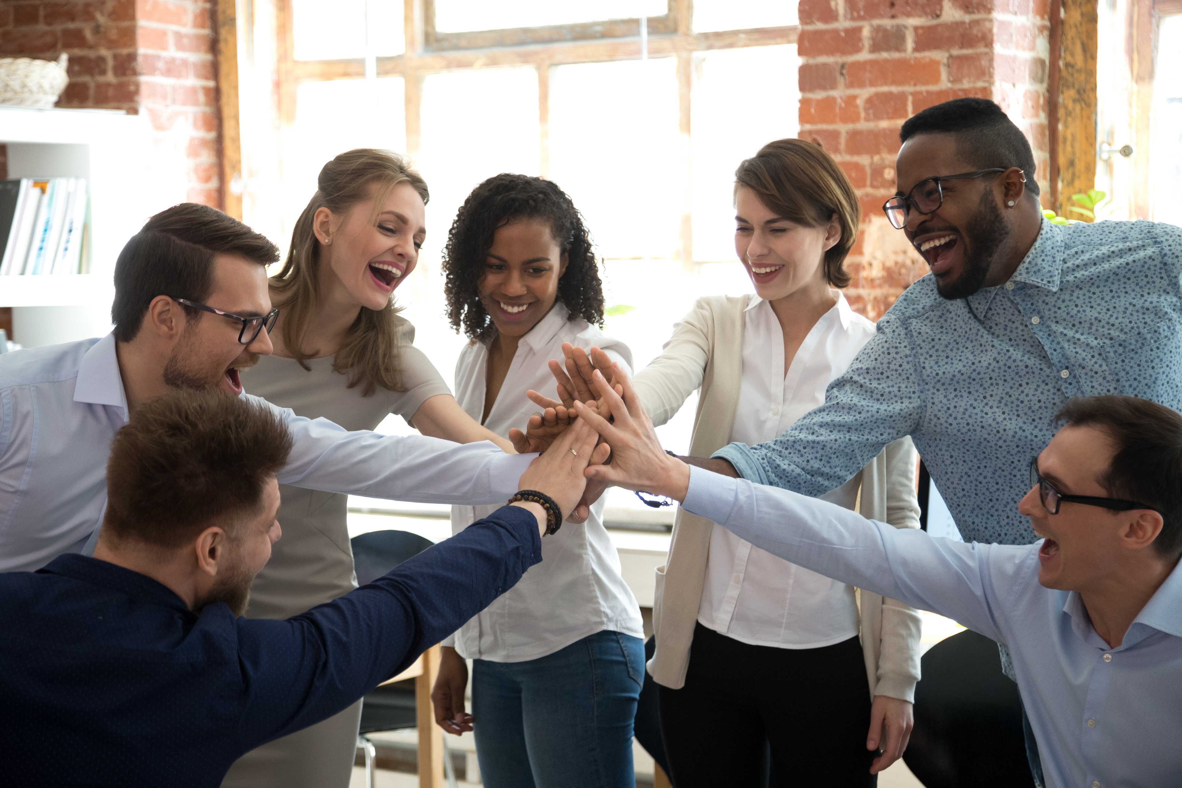 A diverse team of professionals sharing a group high-five in the office