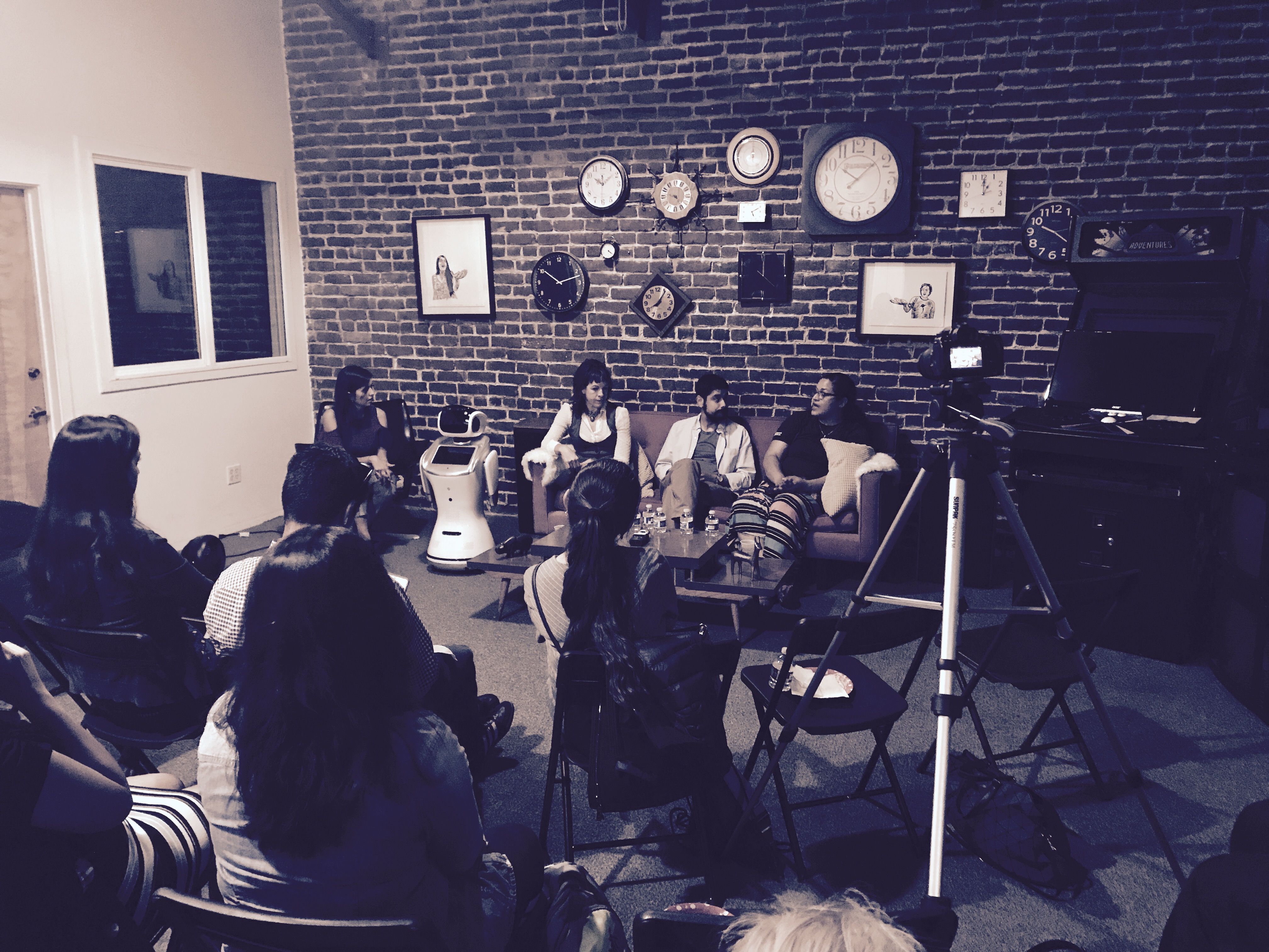 Panel discussion with a Sanbot robot on stage and the audience seated in a circle inside a brick-walled venue