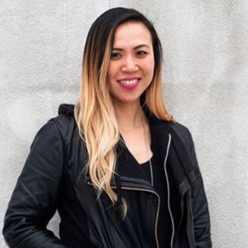 Diana Chow, UX/UI designer, in a black leather jacket smiling against a grey wall