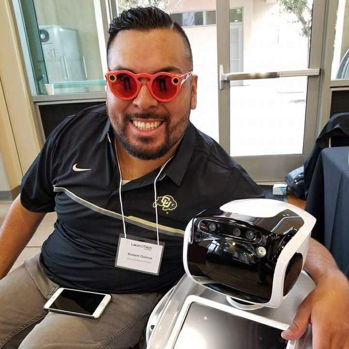 An attendee wearing red Snapchat Spectacles holding the head of a Sanbot robot