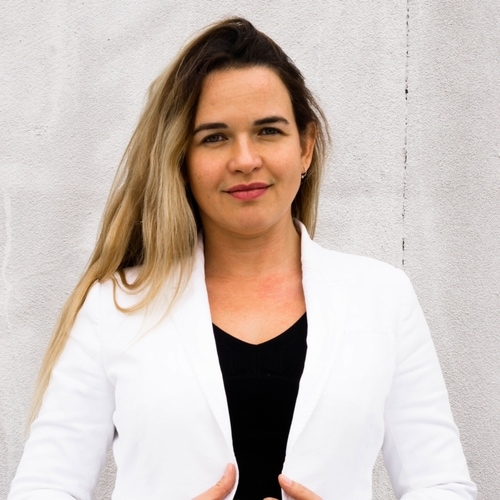 Camila Santos, marketing, in a white blazer against a grey wall