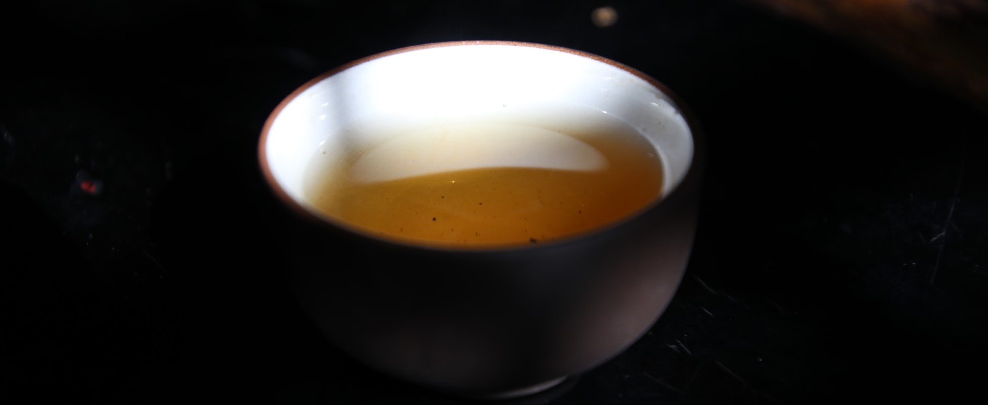 Close-up of a ceramic bowl of golden wellness tea on a dark background