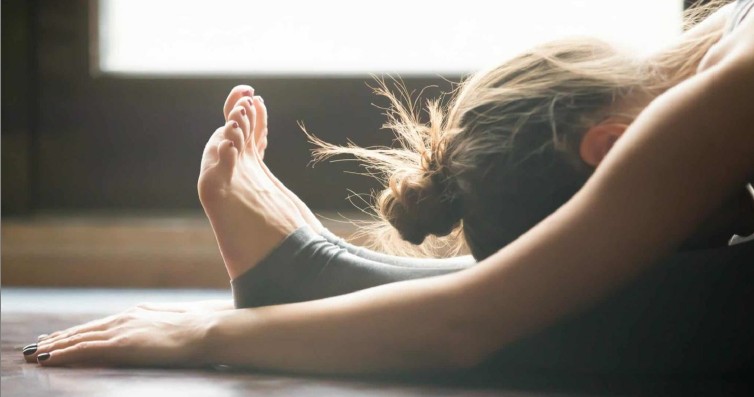 Woman in a deep forward fold yoga stretch on a mat