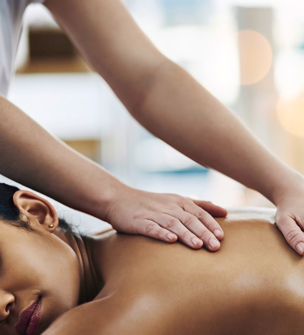 Therapist's hands performing a back massage on a guest at The Wellness Spa