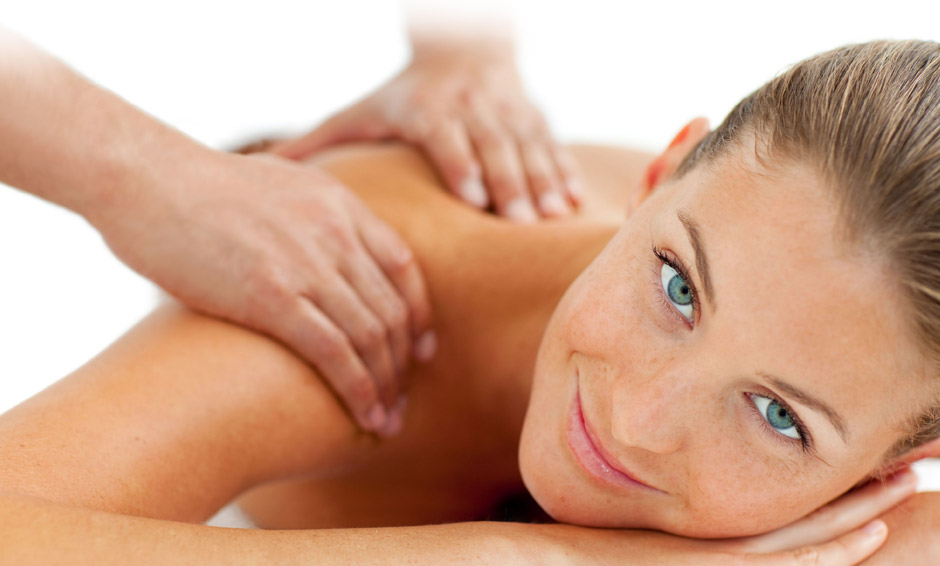 Smiling woman looking at the camera while receiving a shoulder and back massage at The Wellness Spa