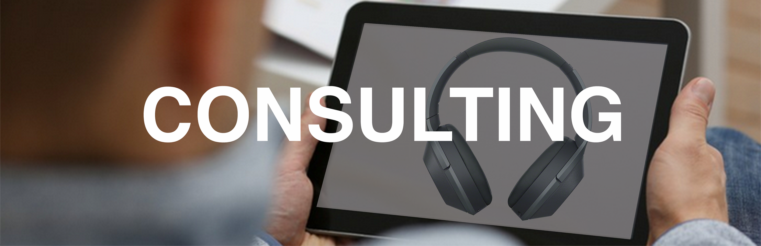 Man holding a tablet showing headphones, with the word CONSULTING across the image