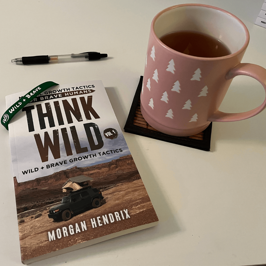 Think Wild Vol. 1 book by Morgan Hendrix beside a pink tree-print mug of tea