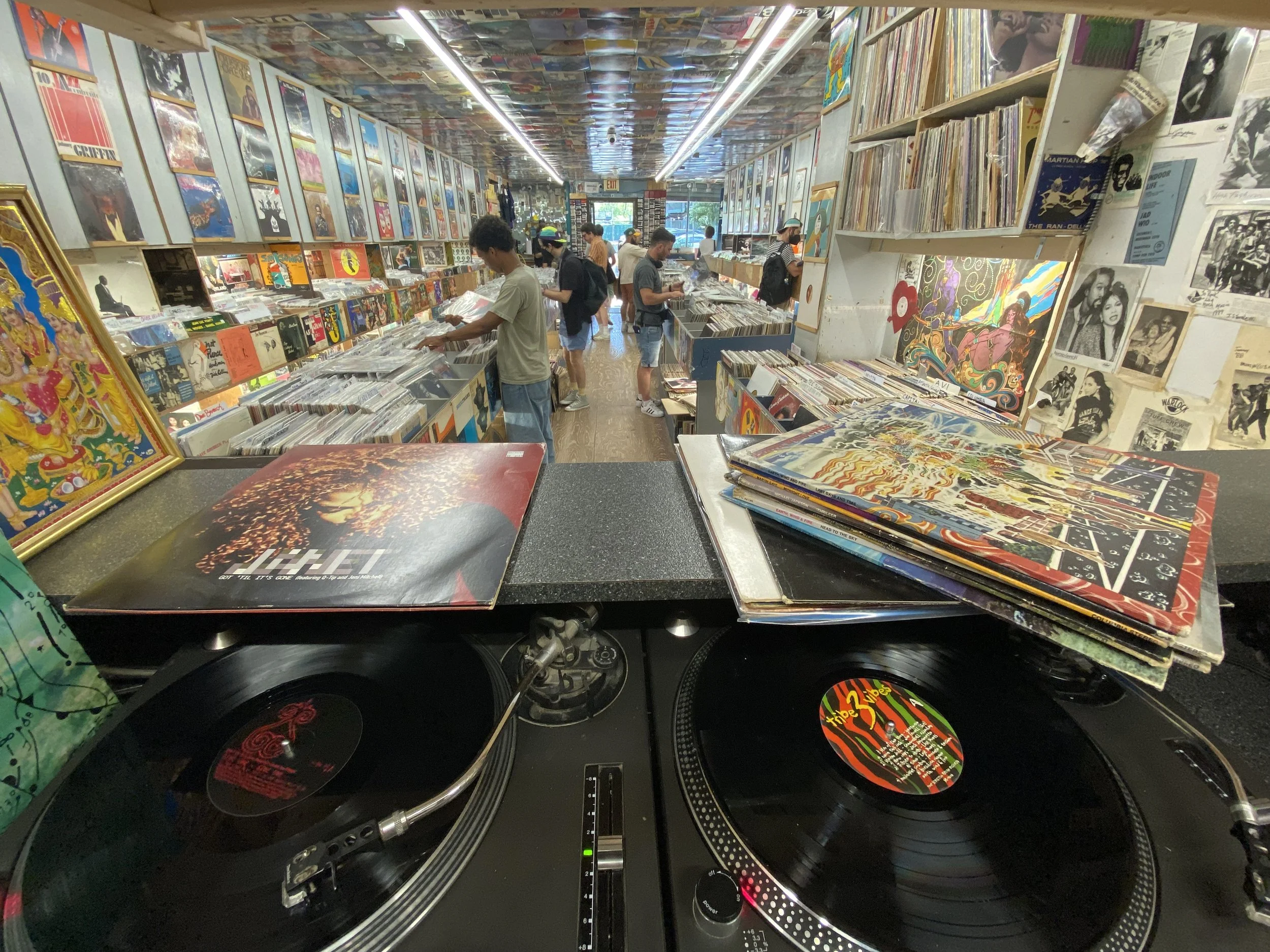 Interior of A-1 Record Shop seen from behind the DJ turntables, customers browsing the vinyl bins