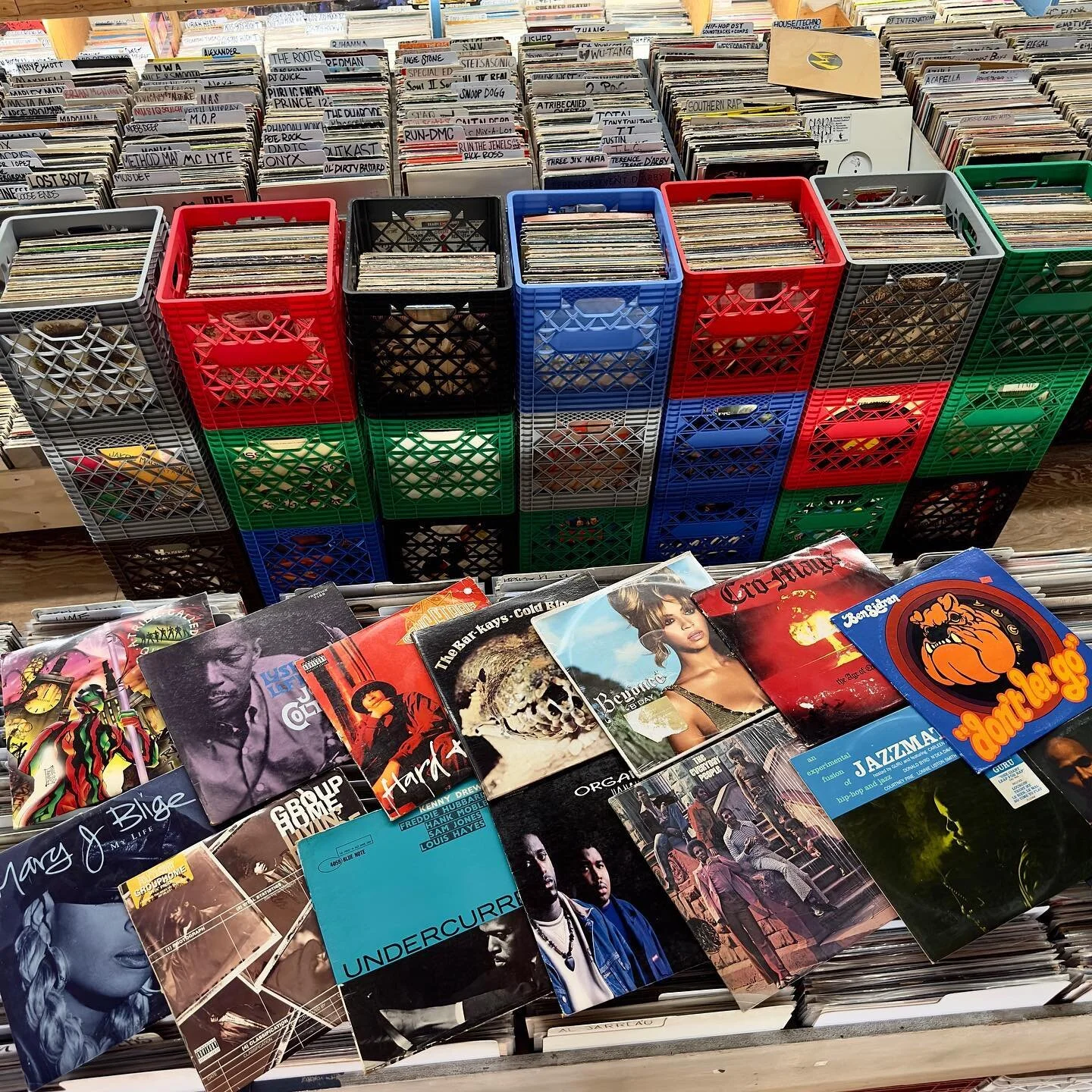 Stacked milk crates of vinyl with album covers including Mary J. Blige and Beyoncé spread in front