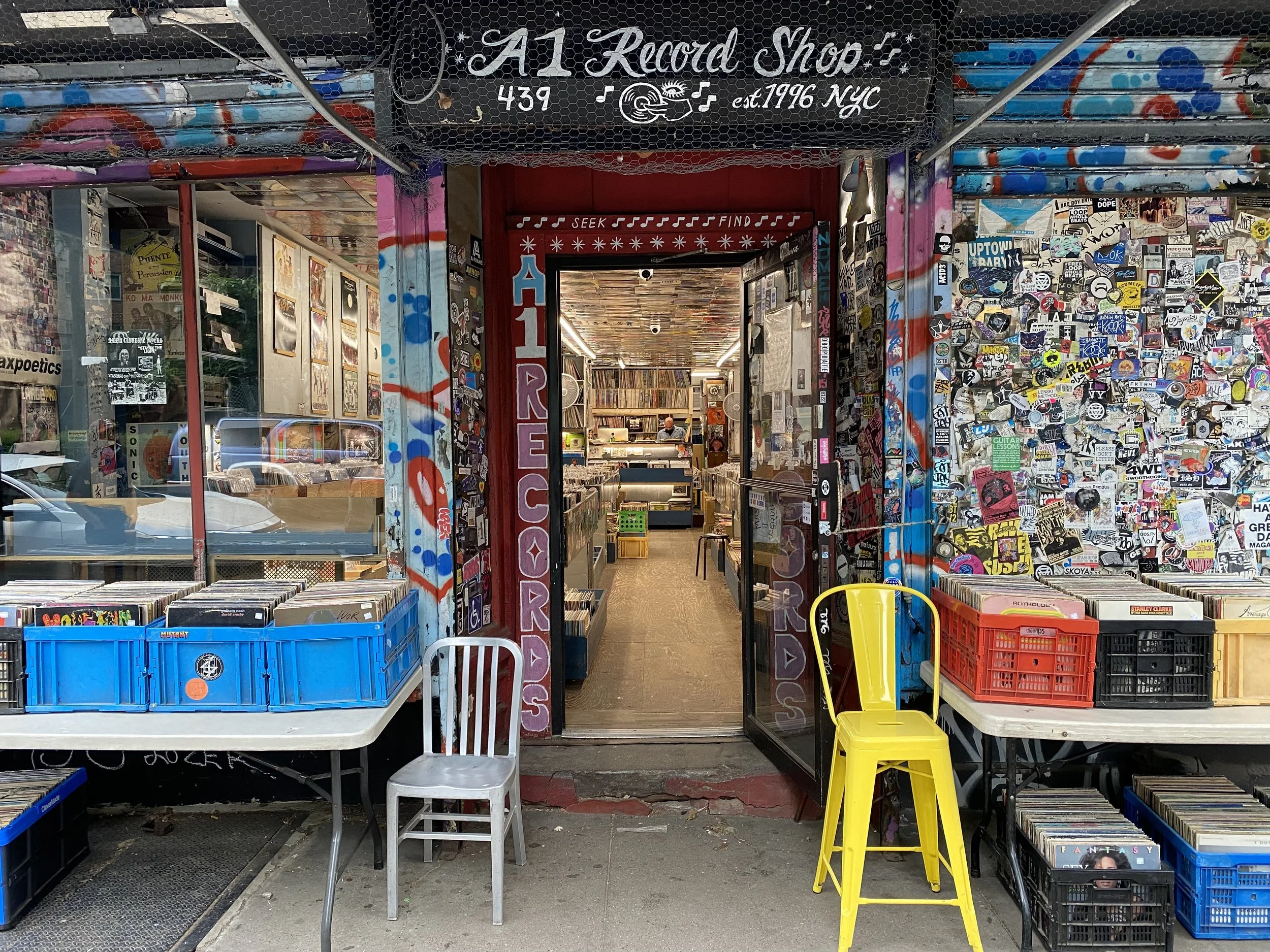 Exterior storefront of A-1 Record Shop at 439 E 6th St, graffiti and sticker-covered facade with records displayed outside on tables