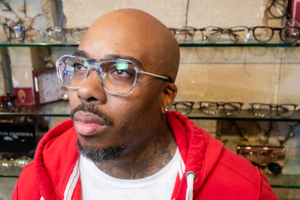 A smiling customer in sunglasses outside the Anthony Aiden storefront
