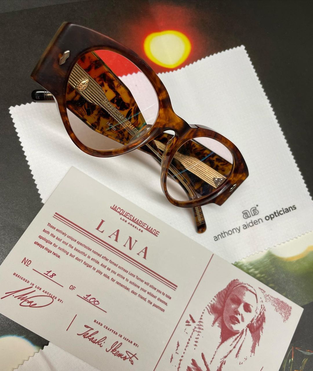A tortoiseshell frame beside a numbered Jacques Marie Mage Lana certificate card