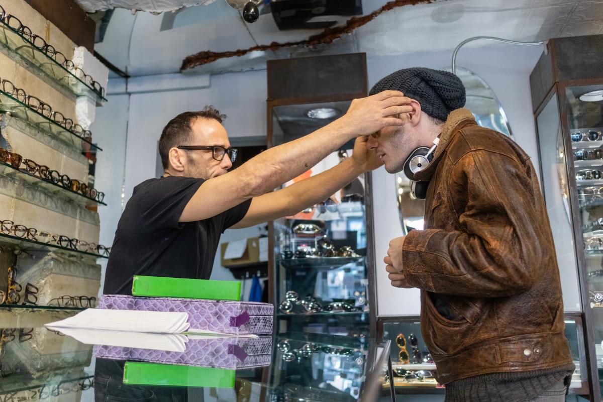 A customer in a red hoodie wearing clear designer frames inside the shop