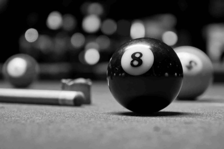 8-ball resting on the felt of the pool table