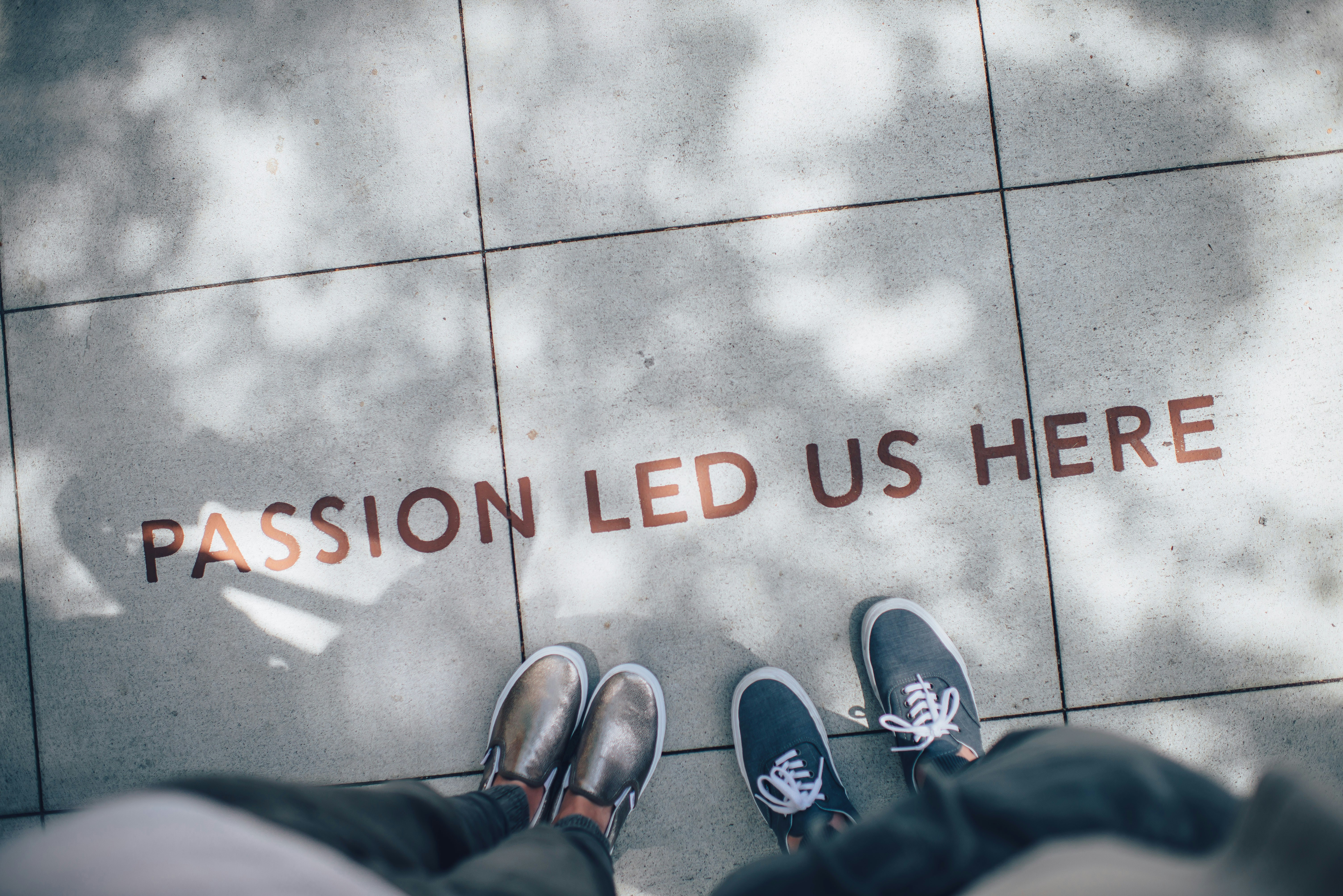Two people seen from above standing on pavement engraved PASSION LED US HERE
