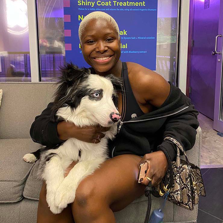 Woman with short platinum hair holding a Border Collie puppy in the DOGMA spa