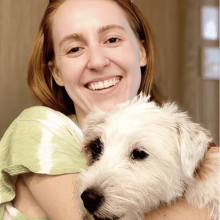 Red-haired woman holding a small white terrier against her cheek