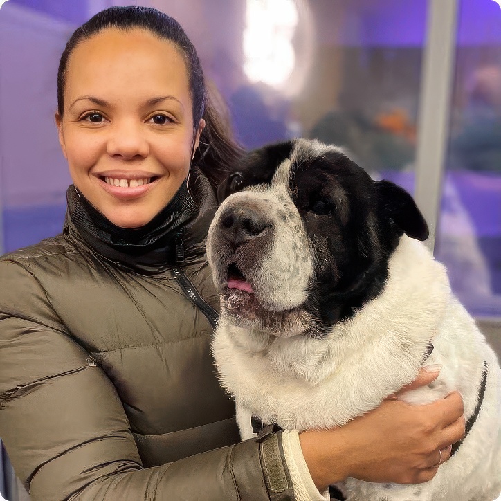 Woman in a puffy jacket holding a black and white bulldog mix
