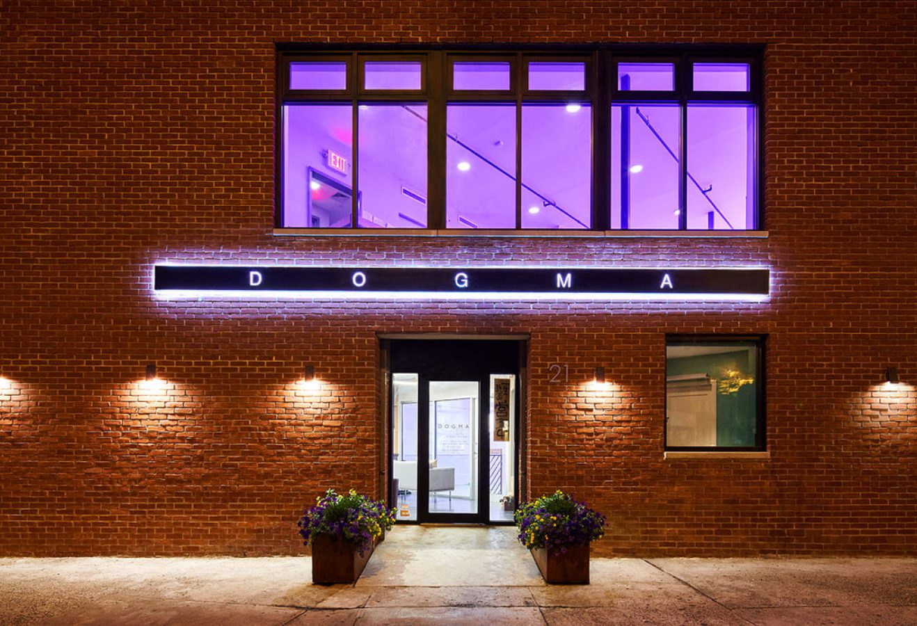 DOGMA's West Village exterior at night with the illuminated DOGMA marquee sign