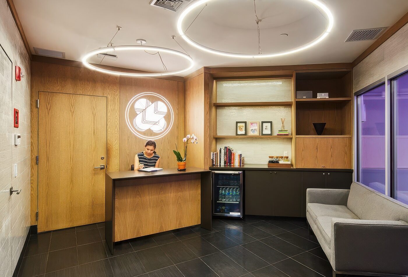 DOGMA reception lobby with a wooden desk and circular neon logo on the wall