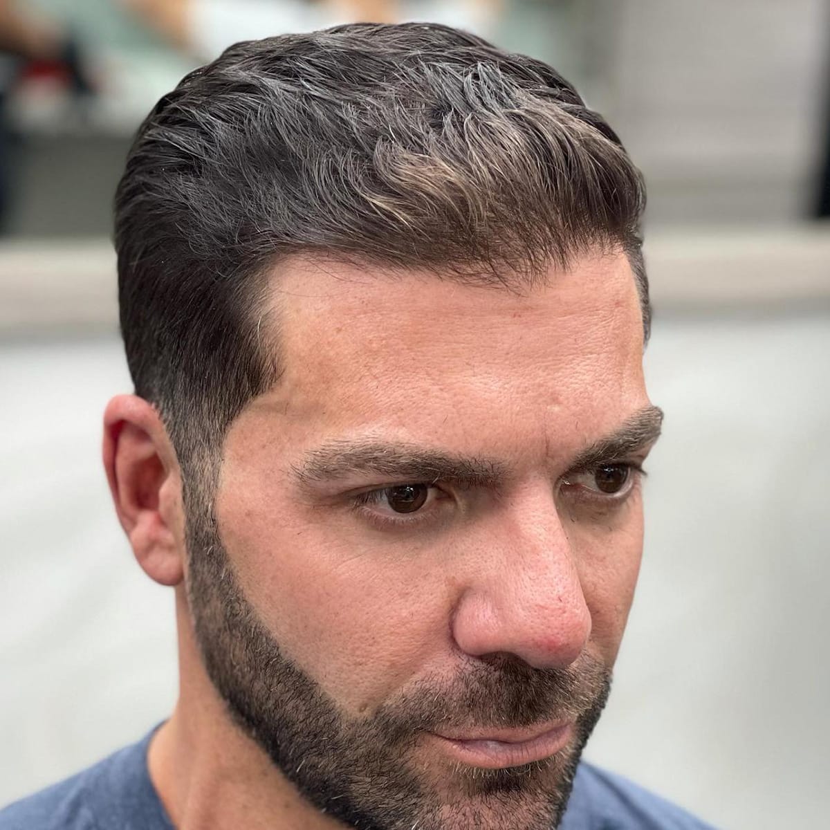Close-up of a side-part slick-back with low fade and short beard