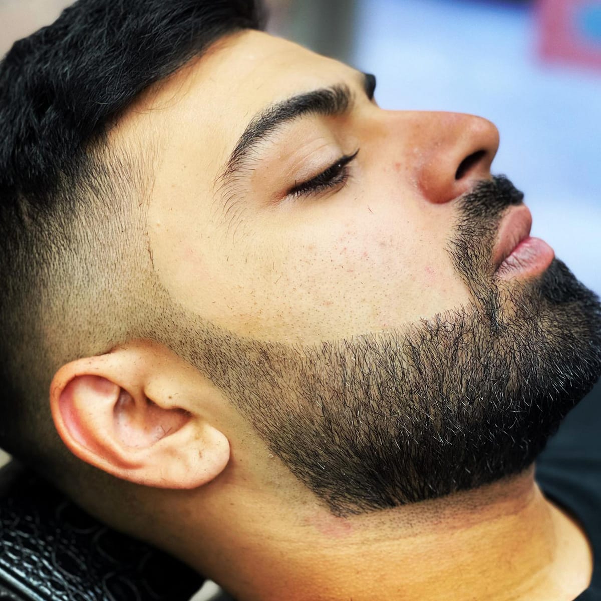 Close-up of a beard trim and fade, face tilted up showing the jawline