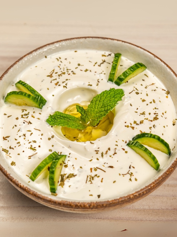 Lebanese labneh yogurt dip in a ceramic bowl with cucumber slices, mint and olive oil