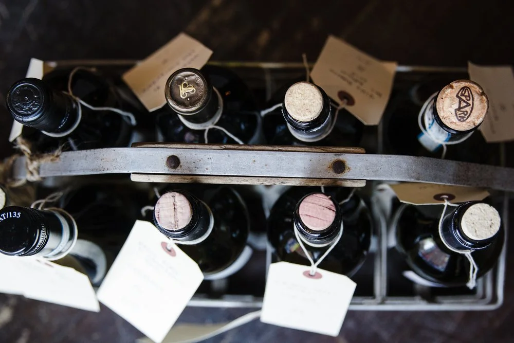 Wine bottle tops with cork and paper tags in a metal carrier
