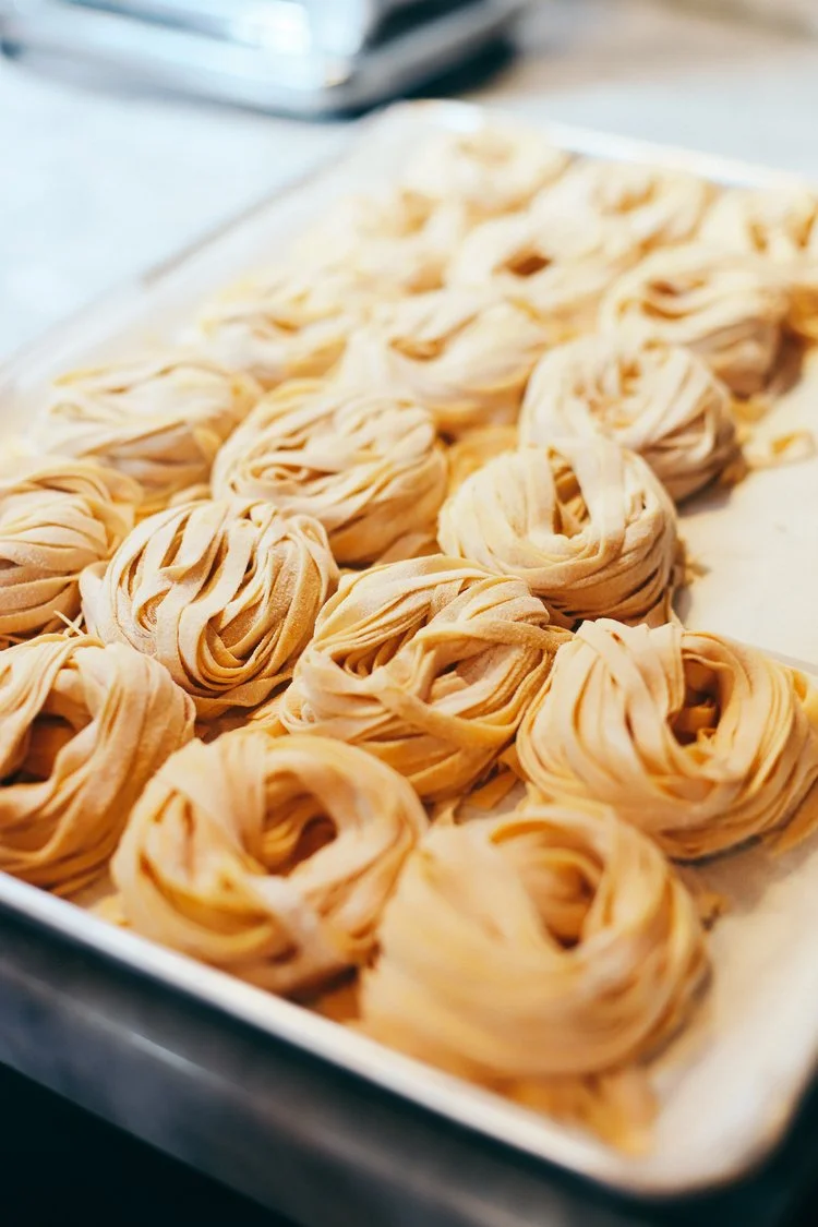 Nests of fresh tagliatelle and pappardelle on a metal baking tray